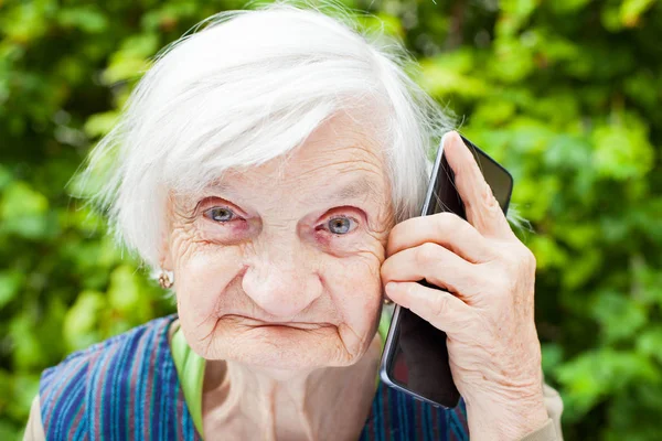 Счастливая улыбающаяся бабушка разговаривает по мобильному телефону — стоковое фото