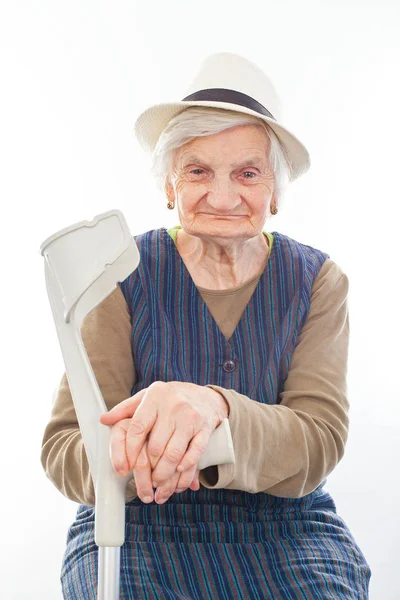 Gehandicapte senior vrouw met kruk binnenshuis — Stockfoto