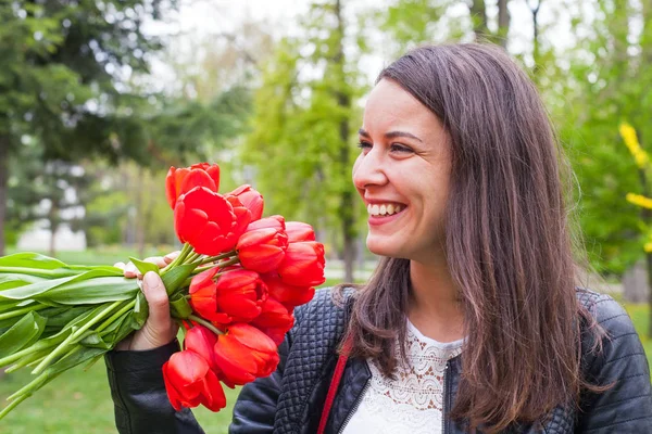 Прекрасная женщина с красными тюльпанами в парке — стоковое фото