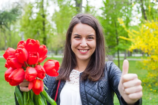 Prachtige vrouw met rode tulpen in het park — Stockfoto