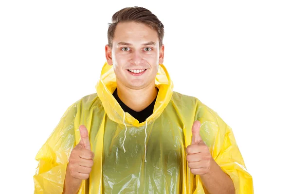 Молодий чоловік у жовтому плащі, показуючи великі пальці вгору — стокове фото