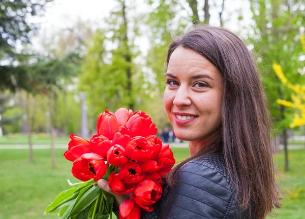 在公园里的红色郁金香的华丽女人 — 图库照片