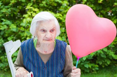 Bir kalp tutan yaşlı bayan balon şeklinde