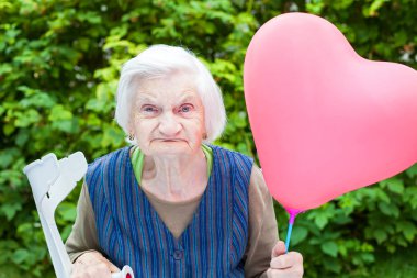 Bir kalp tutan yaşlı bayan balon şeklinde