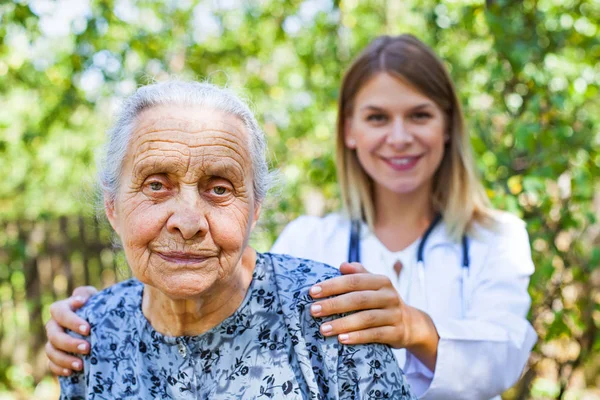 Mulher sênior com médico no parque — Fotografia de Stock