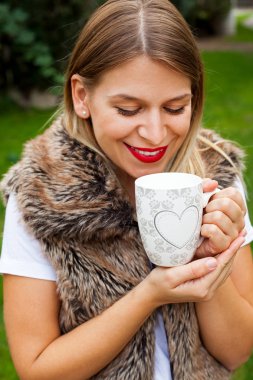 Elinde kahve tutan bir kadın.