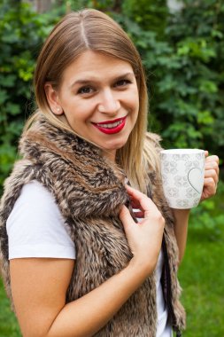 Elinde kahve tutan bir kadın.