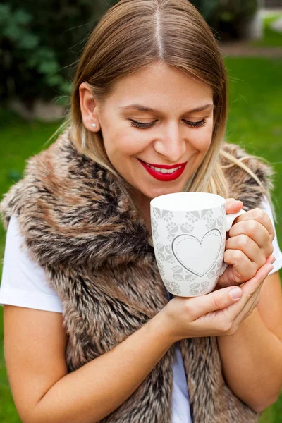 Elinde kahve tutan bir kadın.