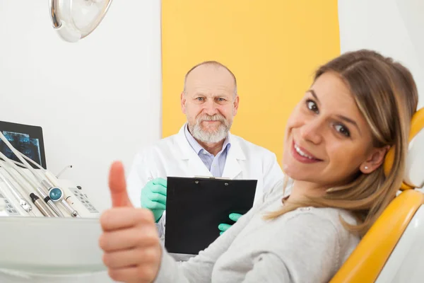 Mulher sorridente no consultório do dentista mostrando os polegares para cima — Fotografia de Stock