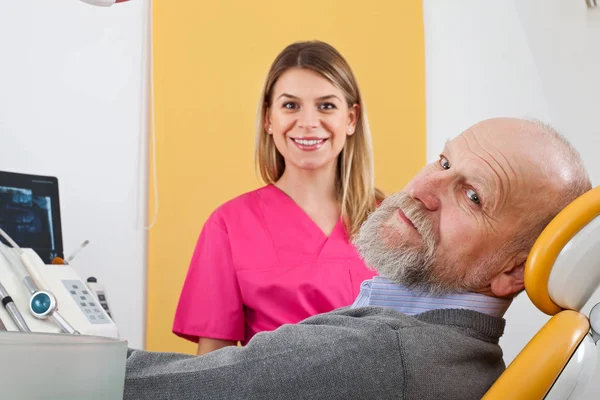 Jovem dentista feminina com paciente idoso — Fotografia de Stock