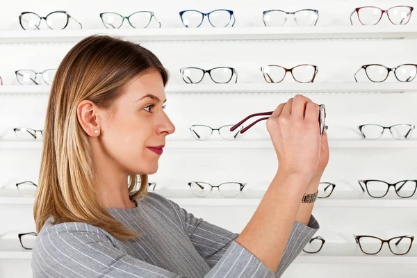 Mujer joven eligiendo marco de gafas — Foto de Stock