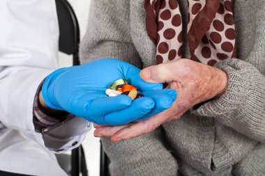 Doktor yaşlı kadına hap veriyor.