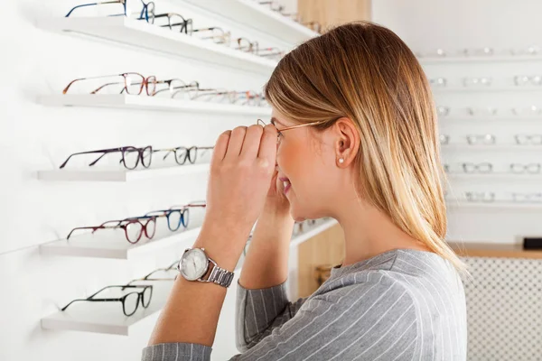 Kobieta patrząc w lustro, optyka sklep — Zdjęcie stockowe