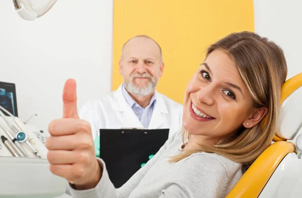 Mulher sorridente no consultório do dentista mostrando os polegares para cima — Fotografia de Stock