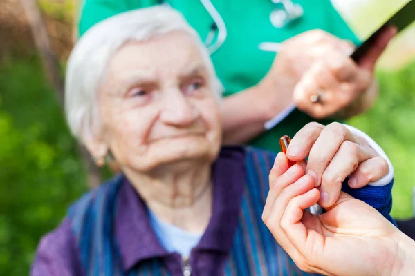 Mujer anciana enferma que recibe pastillas — Foto de Stock