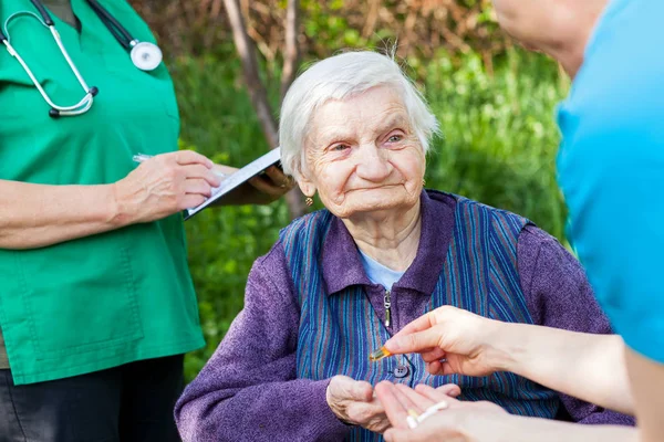 Elderly ill woman receiving pills — Stock Photo, Image