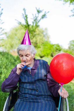 Yaşlı kadın parkta doğum günü kutluyor tekerlekli sandalyede