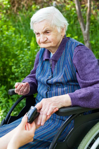 护士用便携式脉搏在公园内测量老年残疾妇女脉搏 — 图库照片