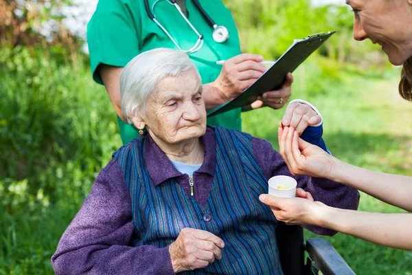 Mujer Anciana Enferma Recibiendo Píldoras Enfermera Aire Libre Médico Escribiendo —  Fotos de Stock