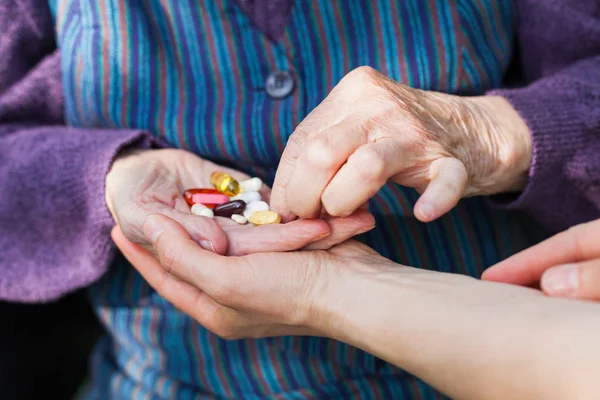 Fotoğrafı Engelli yaşlı kadının el tıbbi ilaçlar caregiver alma kapatmak