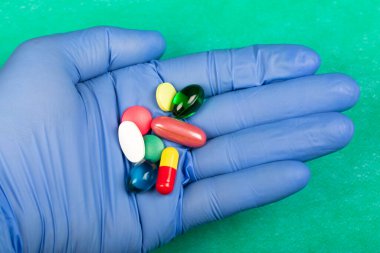 Doktorun elindeki çok renkli ilaç ve vitaminlerin resmini kapat. 