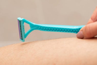 Close up picture of woman holding razor, shaving her hairy leg with folliculitis clipart