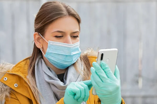 보호용 마스크를 스마트폰 코로나 바이러스 유행병 경보를 장갑을 여성의 — 스톡 사진