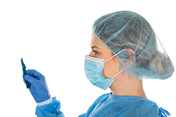 身穿无菌制服的年轻女外科医生在与世隔绝的背景下拿着手术刀 — 图库照片