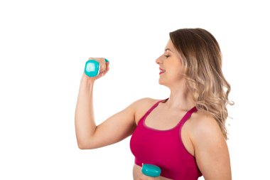 Güzel, aktif bir kadın, arka planda dambıllar tutuyor. Kendini izole etme, vücut çalışma konsepti.