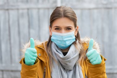 Maskeli ve eldivenli genç ve çekici bir kadın. Coronavirus salgını alarmı. Covid 19