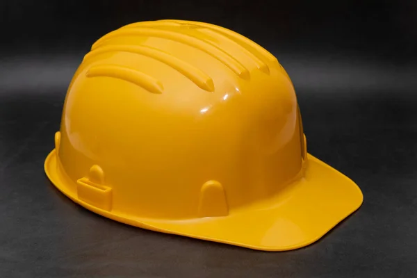 Professional yellow hard hat on dark background. Safety at work concept