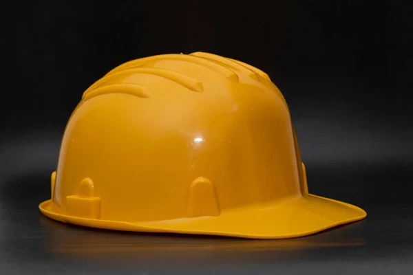 Professional yellow hard hat on dark background. Safety at work concept