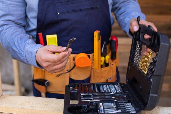 Close up picture of carpenters tool belt and work instruments on wooden background