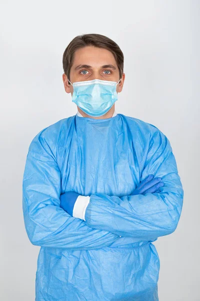 白い背景に外科用マスクと保護スクラブを身に着けている若い男性医師 — ストック写真