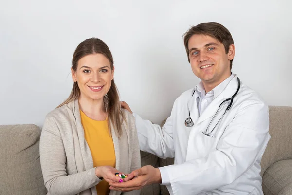 Young male doctor consulting female patient with influenza symptoms at home