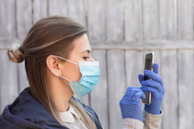 Maskeli ve eldivenli genç bir kadın video konferansı yapıyor, evde çalışıyor - covid-19 salgını