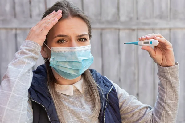 Γυναίκα Μολυσμένη Covid Φοράει Χειρουργική Μάσκα Και Κρατώντας Ψηφιακό Θερμόμετρο — Φωτογραφία Αρχείου