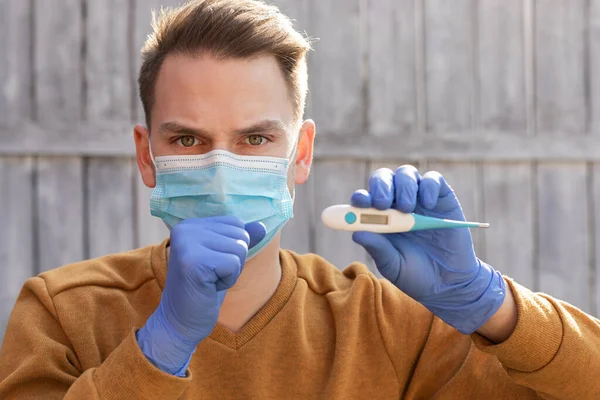 Retrato Joven Contaminado Con Covid Lleva Máscara Guantes Sosteniendo Termómetro —  Fotos de Stock