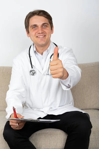 Usmívající Lékař Sedící Gauči Ukazující Palce Nahoru — Stock fotografie