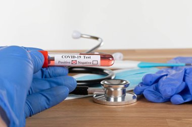 Tahta arka planda pozitif covid-19 kan testi ve tıbbi malzemeler, tedavi, maske ve eldivenlerin fotoğrafını çek