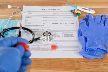 Tahta arka planda pozitif covid-19 kan testi ve tıbbi malzemeler, tedavi, maske ve eldivenlerin fotoğrafını çek