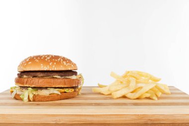 Sebzeli lezzetli çizburger ve susamlı çörek ve ahşap masada patates kızartması.
