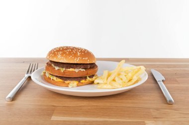 Sebzeli lezzetli çizburger ve susamlı çörek ve ahşap masada patates kızartması.