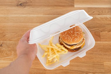 Lezzetli hamburger ve patates kızartması beyaz plastik bir eve servis kutusunda.