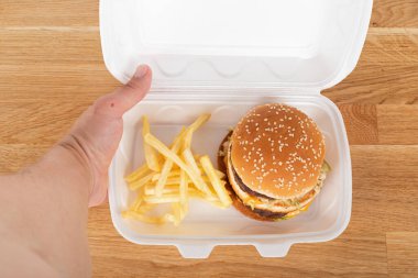 Lezzetli hamburger ve patates kızartması beyaz plastik bir eve servis kutusunda.