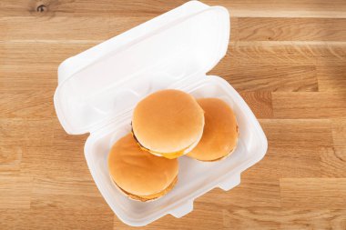 Tahta masadaki beyaz plastik kutuda nefis bir hamburger.
