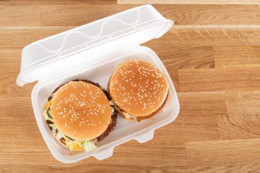 Tahta masadaki beyaz plastik kutuda nefis bir hamburger.