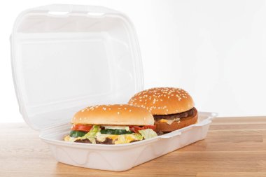 Tahta masadaki beyaz plastik kutuda nefis bir hamburger.