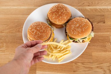 Sebzeli lezzetli çizburger ve susamlı çörek ve ahşap masada patates kızartması.