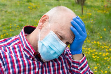 Dışarıdaki tekerlekli sandalyede oturan cerrahi maskeli yaşlı bir adam - enfeksiyon kapma riski